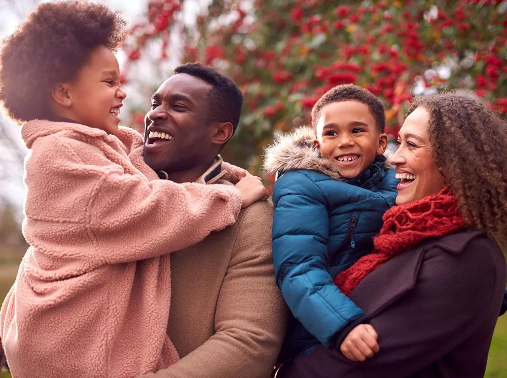 Family hugging and laughing outdoors